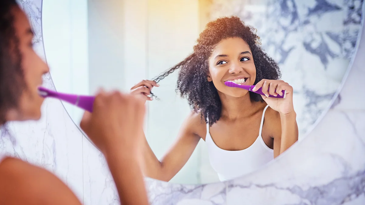 A happy woman bruahing her teeth at sunrise
